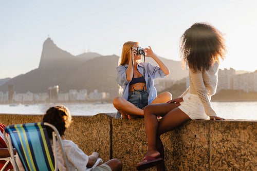 Tourists enjoying sunset on Urca's Wall with Corcovado Hill view