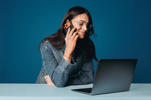 Aspiring young entrepreneur on phone call with laptop in studio setting