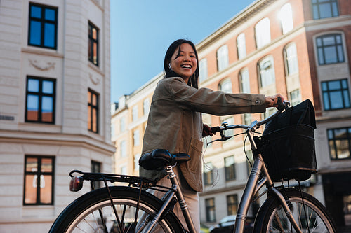 Young woman smiling with bicycle on city street