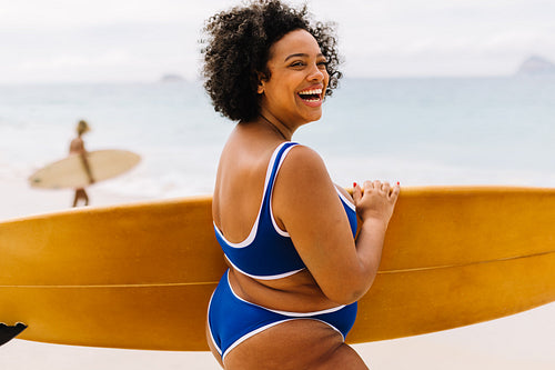 Curvy young woman having fun on a surfing vacation at the beach