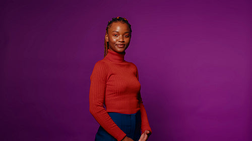 Confident young woman smiles for a portrait in a purple studio