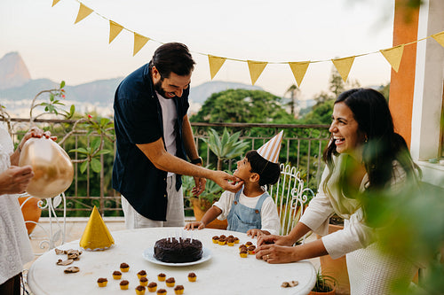 Family celebrating a birthday with cake and decorations outdoors