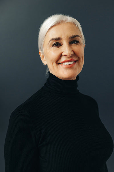 Portrait of a happy senior woman with silver hair standing in a studio
