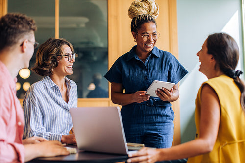 Diverse coworkers discuss ideas at a meeting with laptops and tablets