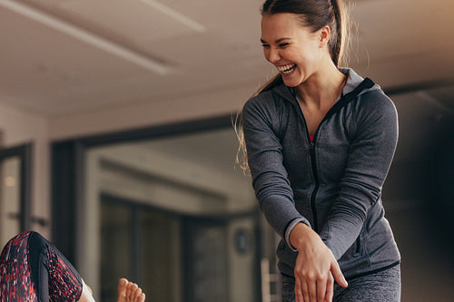 Smiling pilates trainer training woman at the gym