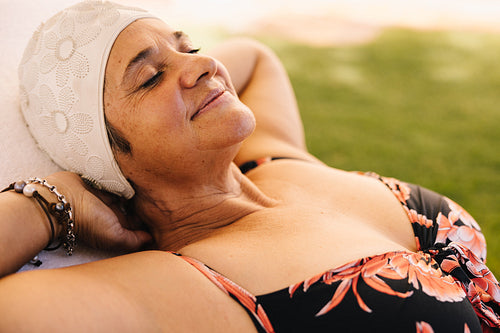Blissful senior woman relaxing on a lounger in swimwear