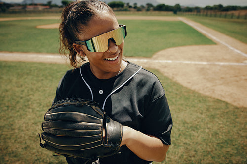 Professional female baseball player wearing sunglasses standing near the baseline with a glove