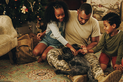 Happy military family playing with their cat at Christmas