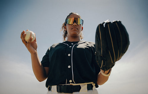Confident baseball pitcher holding mitt and ball wearing sunglasses
