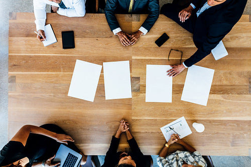 Business people sitting around a table with blank sheets