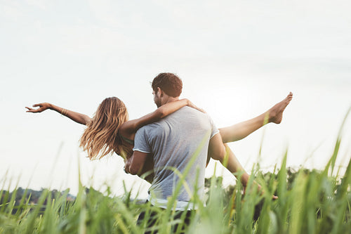 Man carrying woman in rural field