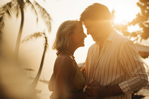 Romantic couple embracing at sunset on a tropical beach holiday