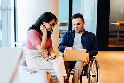 Friends collaborate at work around a laptop