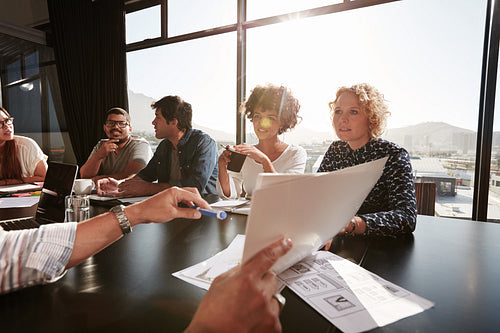Documents in hands of young man explaining project plan to coworkers