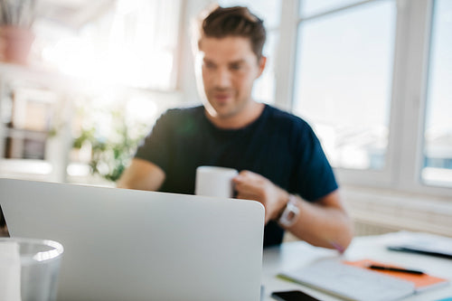Laptop on table with man sitting by
