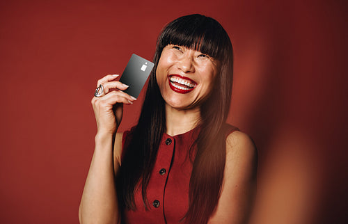Smiling woman holding black card in studio banking portrait