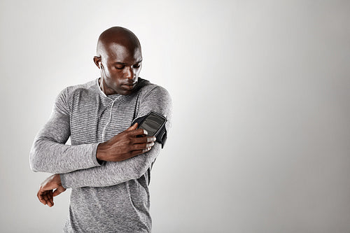 African muscular man listening to music on mobile phone