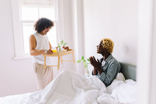 Romantic young gay man treating his lover with breakfast in bed