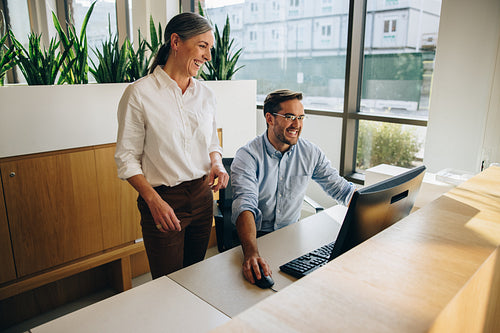 Manager standing by employee working in office