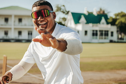 Smiling male cricketer wearing sunglasses on a sunny field