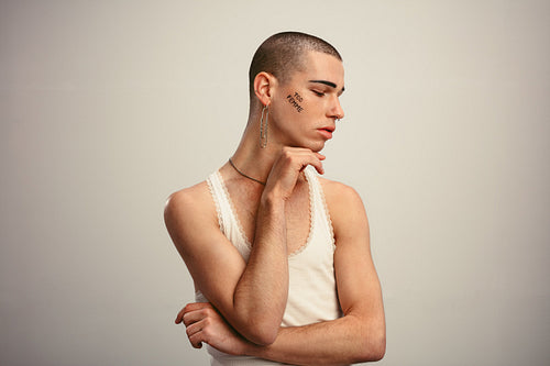 Gender fluid man posing in a tank top and earring