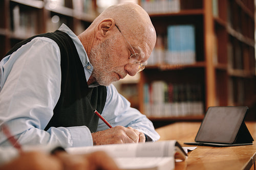 Senior man writing notes sitting in classroom