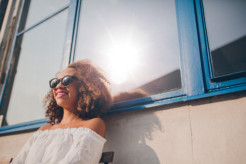 Woman wearing sunglasses sitting outside her house
