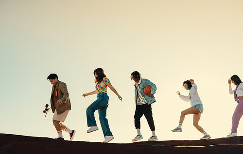 Group of friends moving forward in the sunshine, enjoying youth and having fun