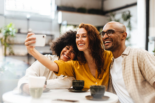 Friends taking a selfie and having fun in a coffee shop