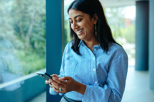 Indian business professional texting in a modern office setting