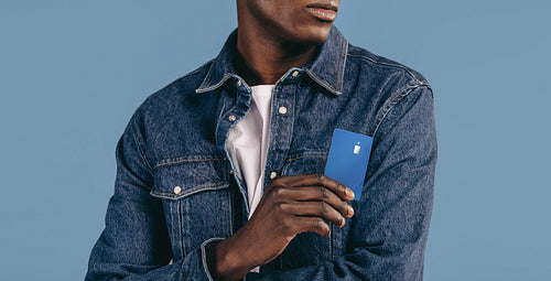 Ready to tap and go, young black man holds his credit card in a studio