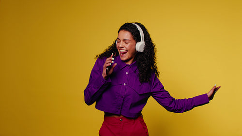 Happy woman sings and dances with headphones and phone