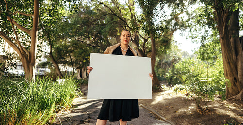 Fashionable woman holding up a placard outdoors