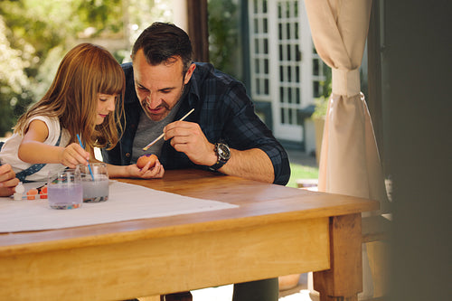 Father and daughter painting easter eggs together