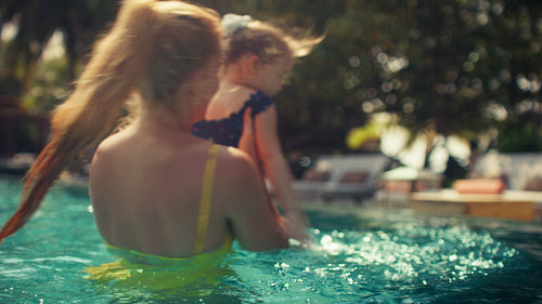 Joyful mother and daughter enjoying playtime together in a beautiful resort pool