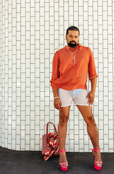 Stylish drag queen standing against a white background
