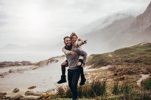 Couple piggybacking along the beach