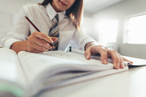 High school girl making notes in book during class
