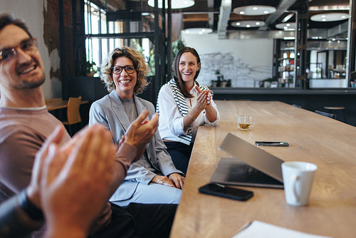 Colleagues applauding during a team meeting in an office
