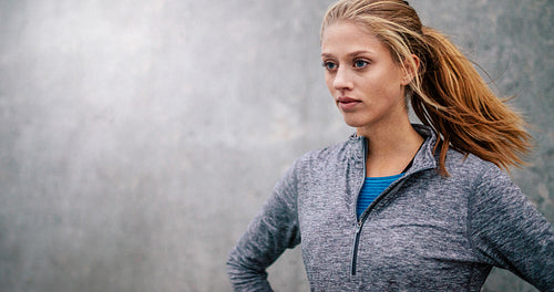 Fit young woman standing outdoors and looking away