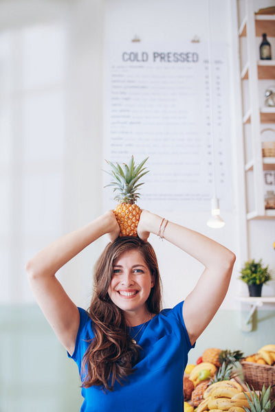 Woman holding a pineapple on her head at juice bar