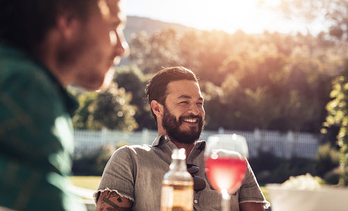 Young man sitting outdoors with friends smiling