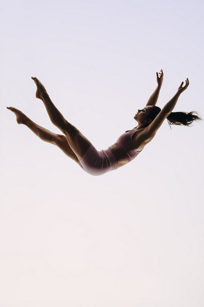In-flight gymnast: A female acrobatics performer leaps mid-air in a graceful routine