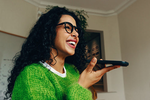 Smiling woman having a phone conversation in an indoor setting