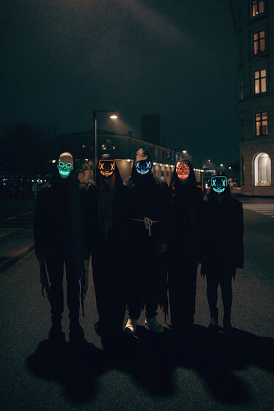 Group wearing glowing masks walking down city street at night
