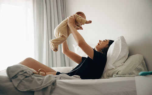 Mother lifting baby and smiling