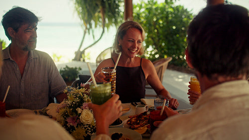 Happy family toasting with fresh juice during a beautiful morning meal at a tropical resort