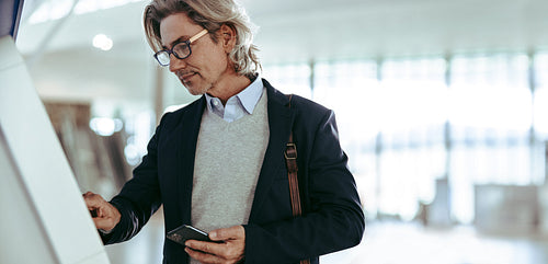 Businessman using self service check in machine at the airport