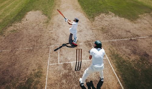 Aerial view of cricket players batting with wicket keeper on field
