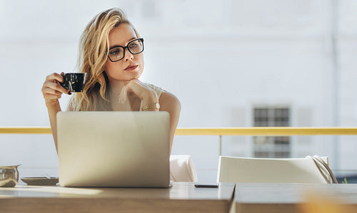 Businesswoman having coffee and thinking at cafe